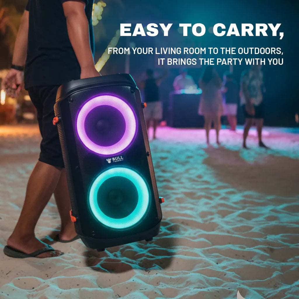 Bull Audio Alpha portable speaker with vibrant purple and teal LED lights carried on beach.